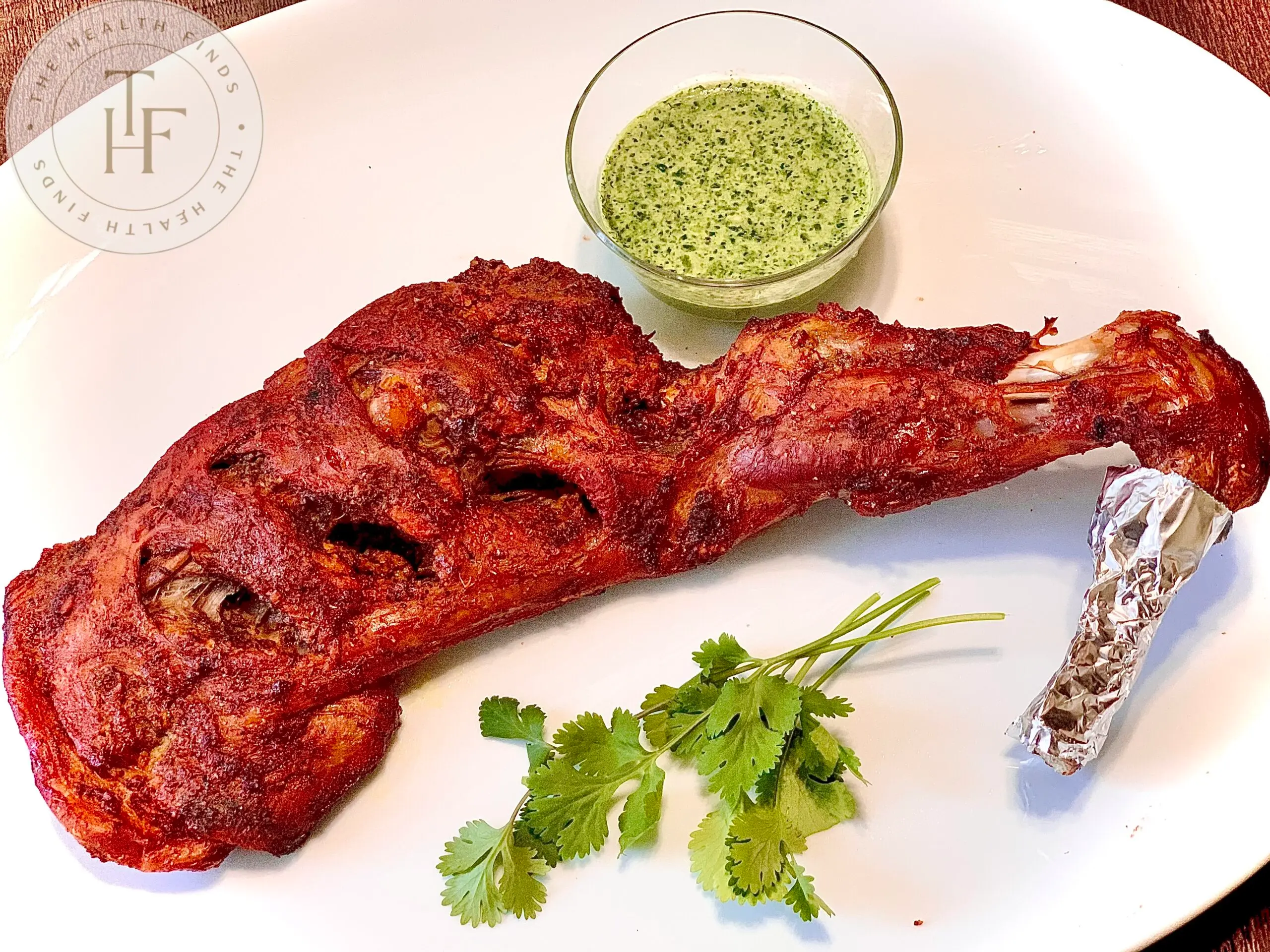 Baked goat leg with green dip and cilantro leaves